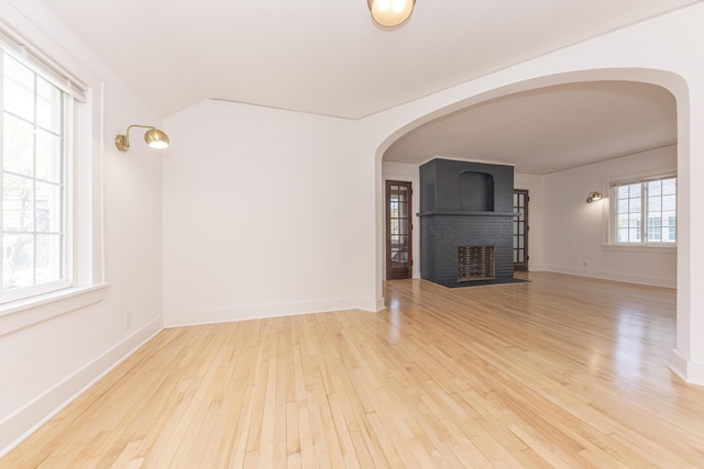 1324 Wells St, Ann Arbor, MI 48104 - unfurnished living room with baseboards, arched walkways, a brick fireplace, and hardwood / wood-style floors