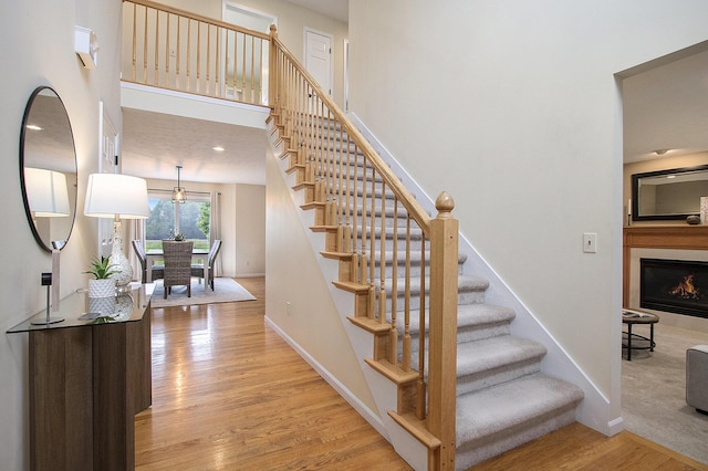 2191 W Linco Rd, Stevensville, MI 49127 - stairway featuring wood finished floors, baseboards, and a lit fireplace