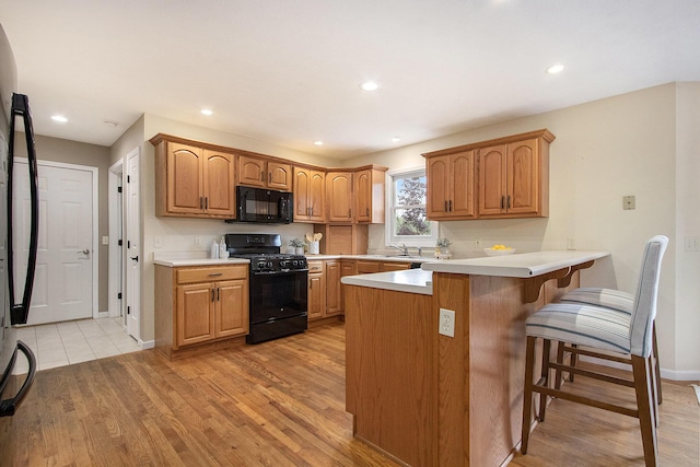 2191 W Linco Rd, Stevensville, MI 49127 - kitchen with black appliances, a sink, a peninsula, a kitchen bar, and light countertops