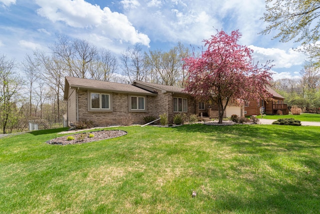 ranch-style house featuring brick siding, a garage, a front yard, and concrete driveway