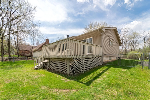 rear view of property with fence, a gate, a lawn, and a deck