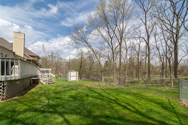 view of yard with fence, an outbuilding, a wooden deck, and a storage unit
