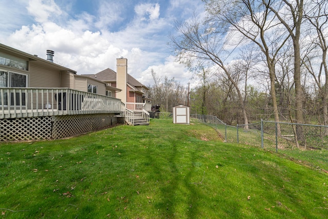 view of yard with fence, a wooden deck, an outdoor structure, and a shed