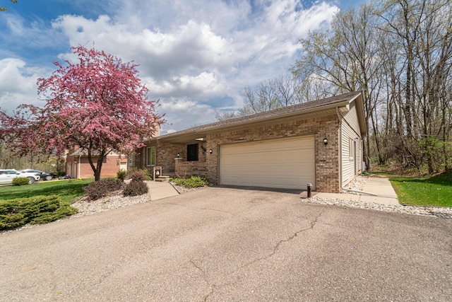 view of front of house featuring an attached garage, brick siding, and aphalt driveway
