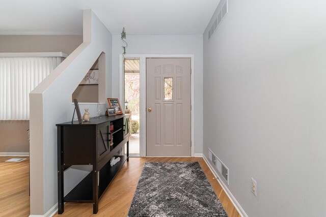 foyer with light wood-style floors, baseboards, and visible vents