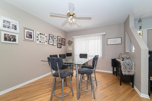 dining room featuring baseboards, a ceiling fan, and light wood finished floors