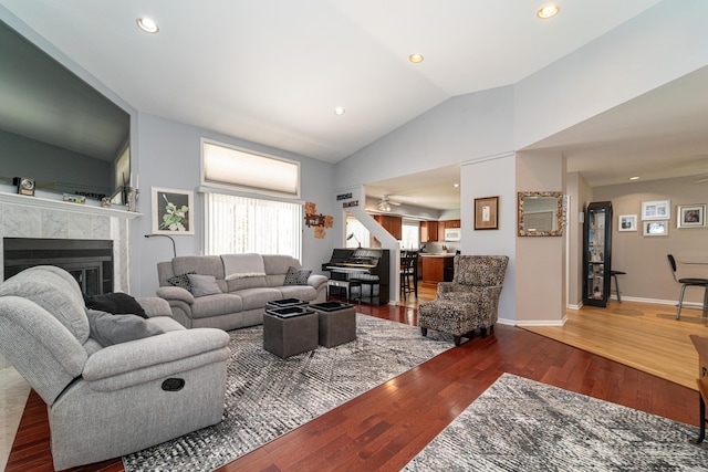 living room with ceiling fan, a tiled fireplace, recessed lighting, wood finished floors, and vaulted ceiling