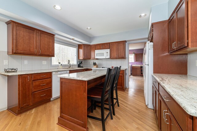 kitchen featuring white appliances, a healthy amount of sunlight, a sink, and light wood-style floors