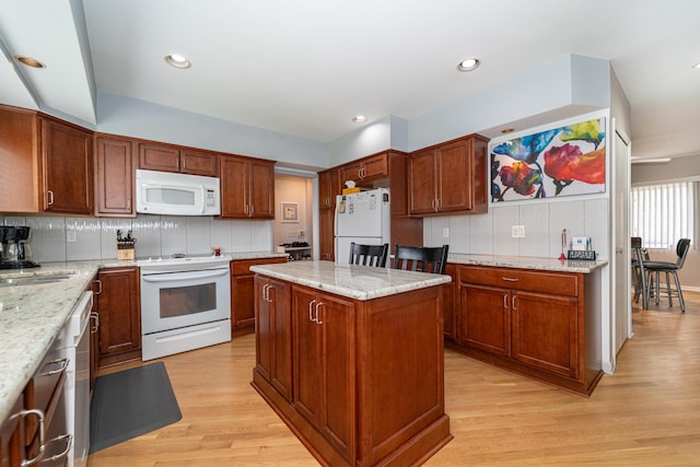 kitchen featuring light wood-style floors, tasteful backsplash, light stone countertops, and white appliances
