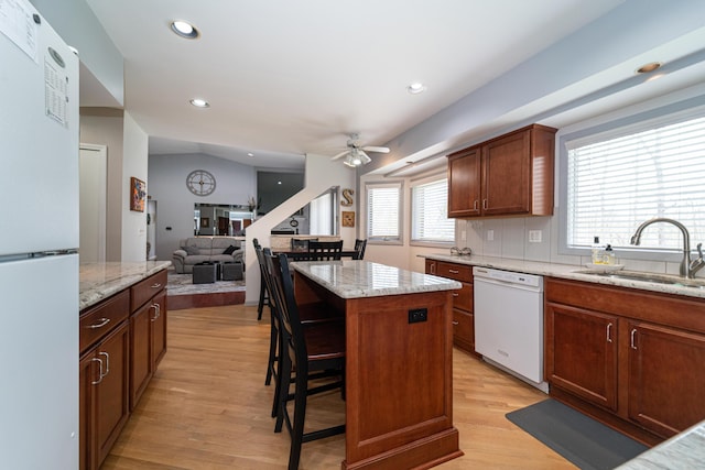 kitchen with a sink, light wood-style floors, white appliances, a ceiling fan, and a kitchen island