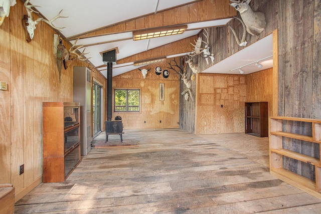 2347 W W Dowling Rd, Delton, MI 49046 - unfurnished living room featuring a wood stove, wood-type flooring, wood walls, vaulted ceiling, and rail lighting