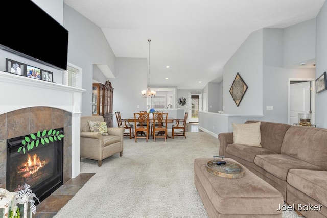 carpeted living area featuring high vaulted ceiling, a chandelier, a healthy amount of sunlight, and a tile fireplace