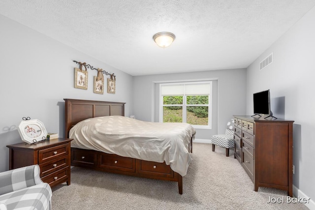 bedroom featuring light colored carpet, a textured ceiling, visible vents, and baseboards