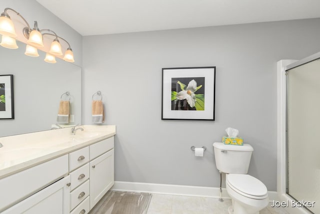 bathroom with a sink, double vanity, toilet, baseboards, and a shower stall