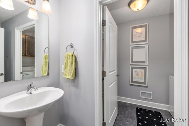 bathroom with visible vents, a sink, baseboards, and a textured ceiling