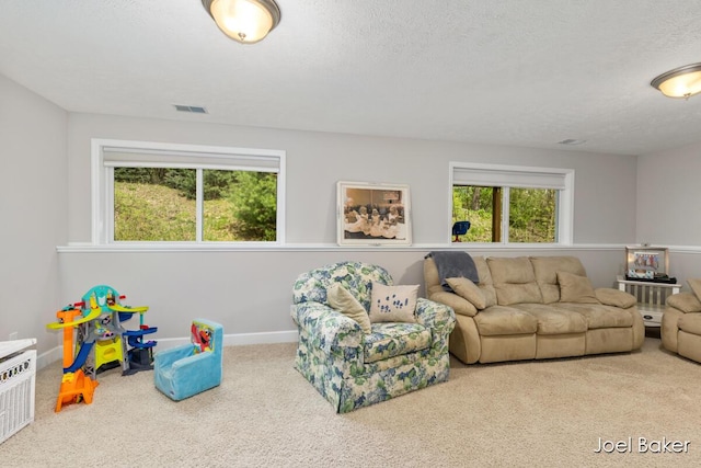carpeted living room featuring baseboards, a textured ceiling, and visible vents