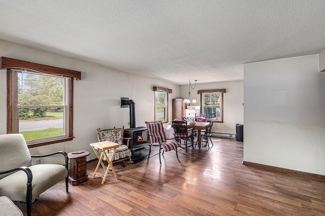 14770 Panu Ave, Kaleva, MI 49645 - living room with wood finished floors, a textured ceiling, a wood stove, baseboards, and a baseboard heating unit