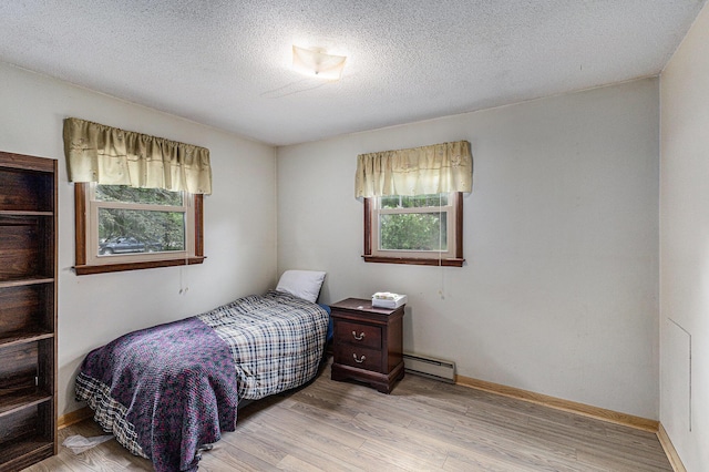 14770 Panu Ave, Kaleva, MI 49645 - bedroom with baseboard heating, light wood finished floors, a textured ceiling, and baseboards