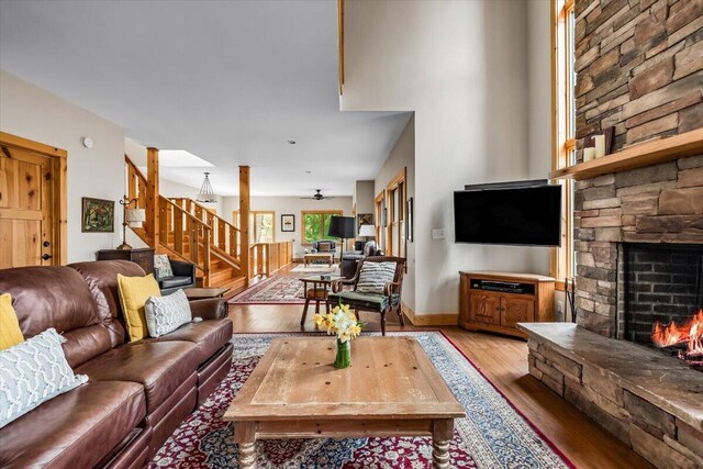 80220 Linden Hills St, Covert, MI 49043 - living room featuring a stone fireplace, stairway, wood finished floors, and a ceiling fan