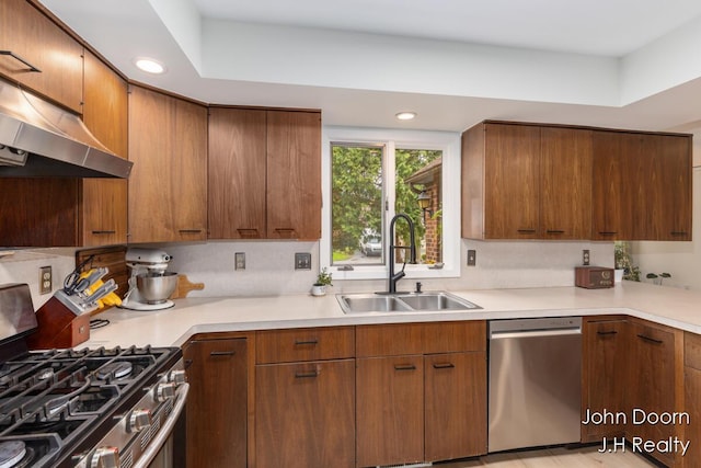 kitchen featuring stainless steel appliances, a sink, under cabinet range hood, light countertops, and recessed lighting