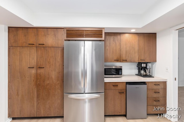 kitchen with appliances with stainless steel finishes, light countertops, brown cabinets, and recessed lighting