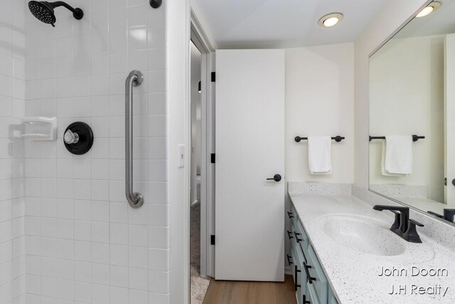 bathroom featuring tiled shower, vanity, and wood finished floors