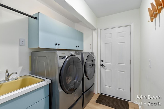 clothes washing area featuring washer and dryer, cabinet space, and light wood finished floors