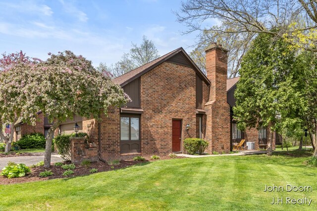 view of front of house with a front lawn, brick siding, a chimney, and driveway