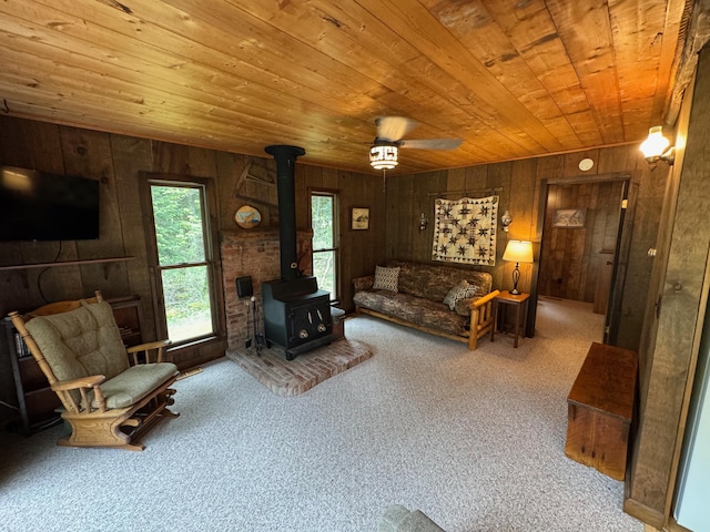 3574 N Comanche Trl, Branch, MI 49402 - carpeted living room with wood ceiling, a wood stove, wood walls, and a ceiling fan