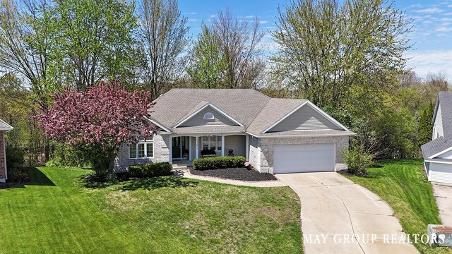 3729 Windshire Dr SE, Grand Rapids, MI 49546 - view of front of house with an attached garage, concrete driveway, covered porch, and a front yard