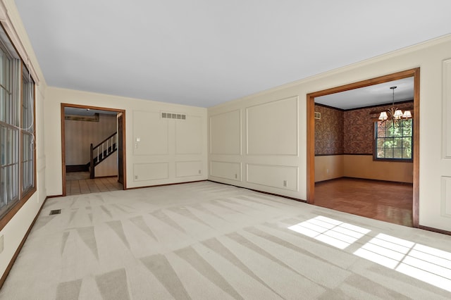 275 S Bluffwood Ter, Saint Joseph, MI 49085 - empty room featuring light colored carpet, a chandelier, wainscoting, ornamental molding, and stairs