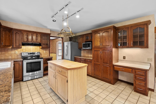 275 S Bluffwood Ter, Saint Joseph, MI 49085 - kitchen with stainless steel appliances, range hood, butcher block countertops, tasteful backsplash, and glass insert cabinets