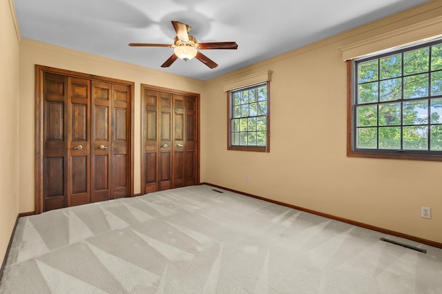 275 S Bluffwood Ter, Saint Joseph, MI 49085 - unfurnished bedroom with two closets, baseboards, carpet floors, crown molding, and a ceiling fan