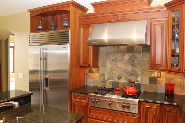 60 Timber Ridge Ct, Milan, MI 48160 - kitchen featuring appliances with stainless steel finishes, wall chimney range hood, arched walkways, backsplash, and glass insert cabinets