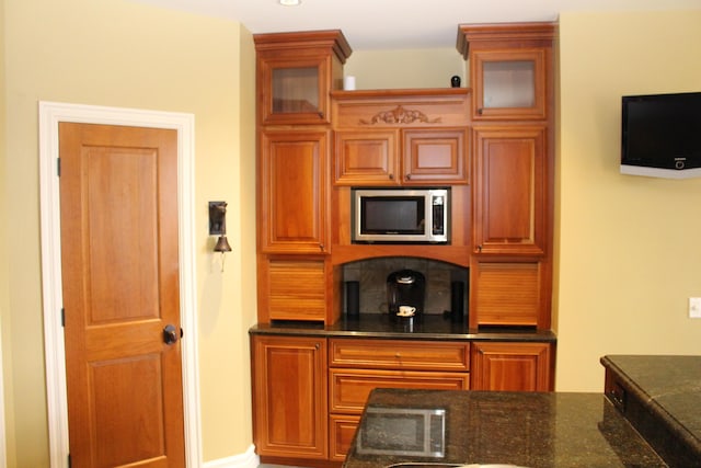 60 Timber Ridge Ct, Milan, MI 48160 - kitchen with stainless steel microwave, glass insert cabinets, dark stone countertops, and brown cabinets