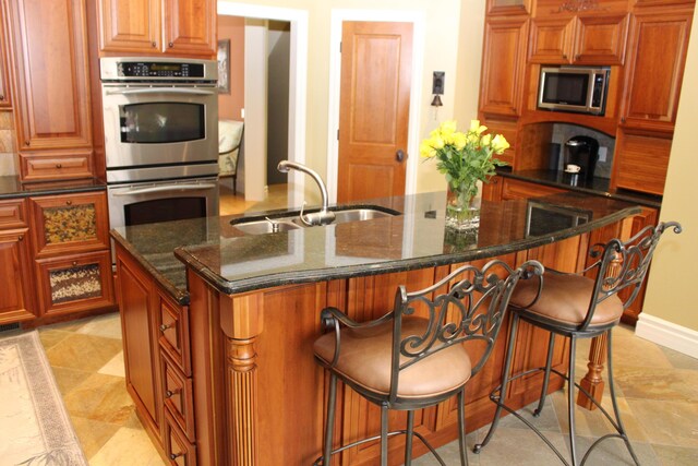 60 Timber Ridge Ct, Milan, MI 48160 - kitchen with stainless steel appliances, a center island with sink, dark stone countertops, and a kitchen breakfast bar