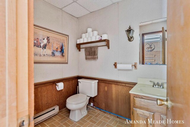 12345 92nd St SE, Alto, MI 49302 - half bathroom with vanity, toilet, a wainscoted wall, a drop ceiling, and a baseboard heating unit