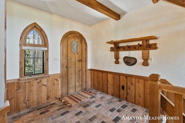 12345 92nd St SE, Alto, MI 49302 - entryway featuring wooden walls, wainscoting, beam ceiling, brick floor, and visible vents