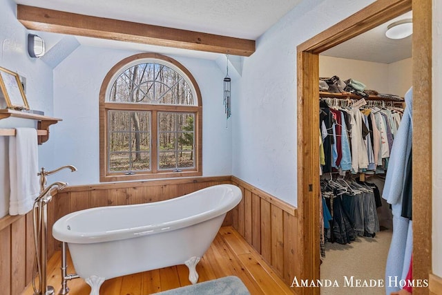 12345 92nd St SE, Alto, MI 49302 - full bathroom featuring wood walls, a wainscoted wall, a freestanding tub, a spacious closet, and hardwood / wood-style flooring