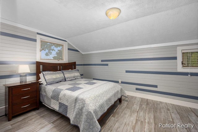 1266 E 88th St, Newaygo, MI 49337 - bedroom featuring wood finished floors, vaulted ceiling, baseboards, wooden walls, and a textured ceiling