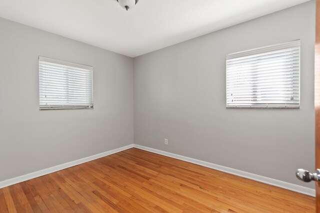 unfurnished room featuring baseboards, plenty of natural light, and wood finished floors