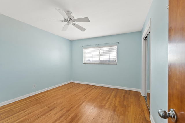 unfurnished bedroom featuring a ceiling fan, baseboards, wood finished floors, and a closet
