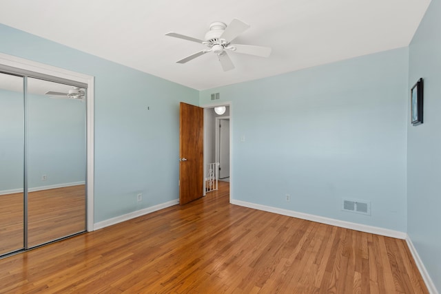 unfurnished bedroom featuring baseboards, wood finished floors, and visible vents