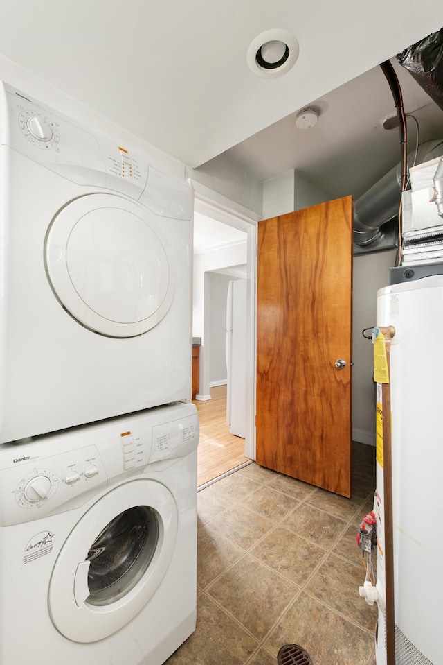 laundry room featuring water heater, stacked washer and clothes dryer, and laundry area