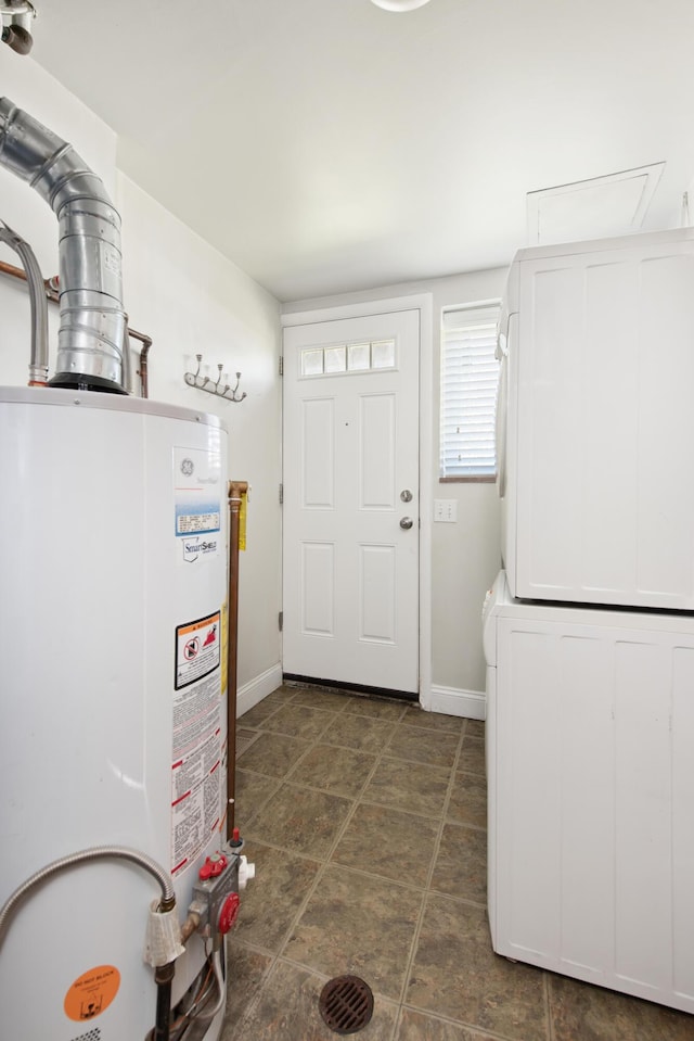 interior space with baseboards, water heater, and stacked washer / dryer
