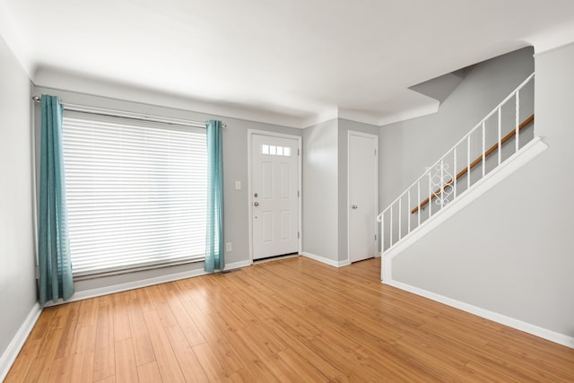 entryway featuring baseboards, light wood finished floors, and stairway