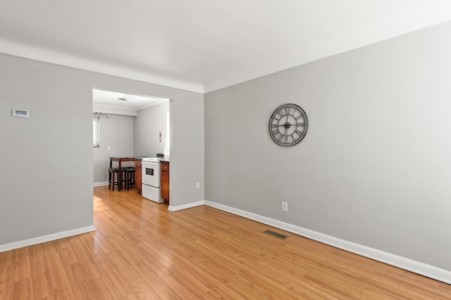 spare room featuring crown molding, baseboards, light wood finished floors, and visible vents