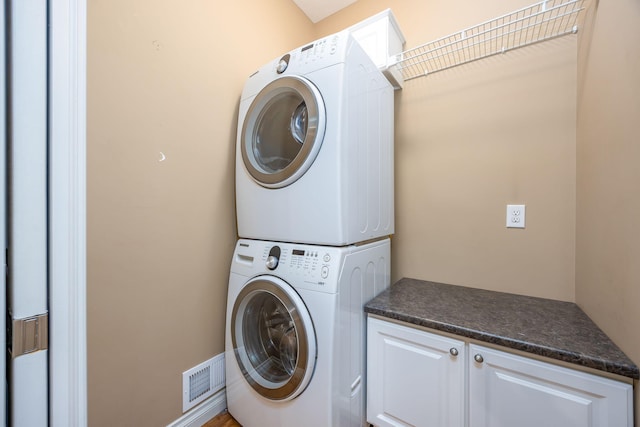 18559 Kreig Dr, Big Rapids, MI 49307 - laundry room with cabinet space, stacked washing maching and dryer, and visible vents