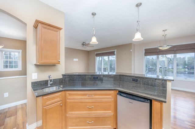 18559 Kreig Dr, Big Rapids, MI 49307 - kitchen with decorative light fixtures, refrigerator, light wood-type flooring, a sink, and dark stone counters