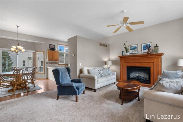 6332 Rush Creek Ct, Hudsonville, MI 49426 - living area featuring a fireplace with raised hearth, light colored carpet, visible vents, and ceiling fan with notable chandelier